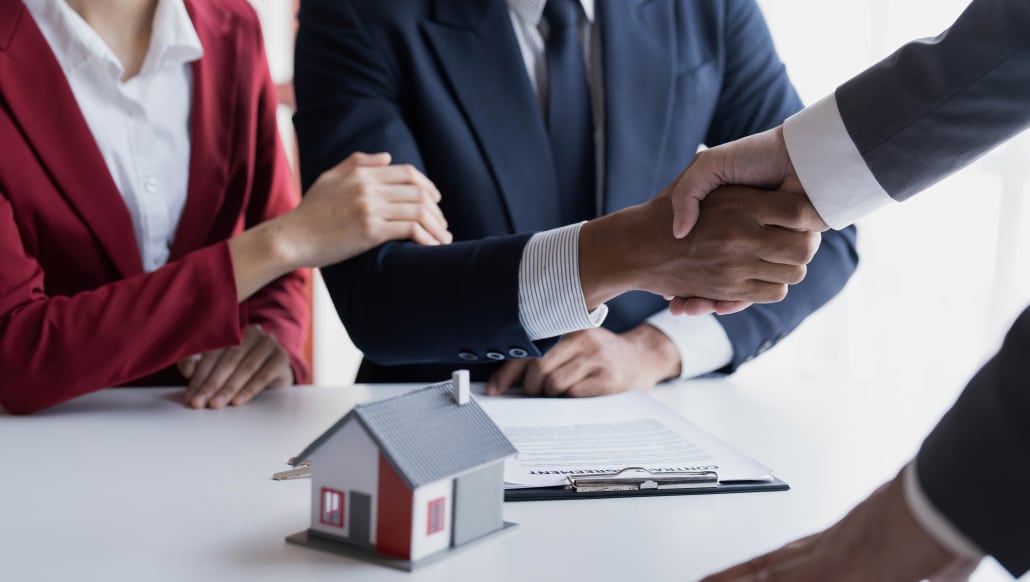 Happy couple first time home owners handshaking property evaluator at meeting, asian family customers make real estate deal for rent house purchase or mortgage investment